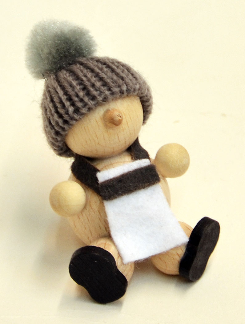 Muñeco de nieve natural, sentado, gorro gris, delantal.